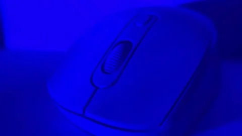 Close-up shot of a computer mouse under colored studio lighting on a clean surfa Stock Footage 326336129