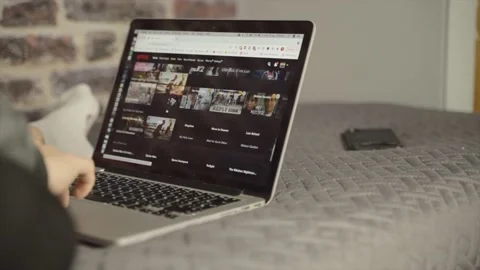 Close up shot of a computer screen as a man scrolls through Netflix films Video stock 165189315