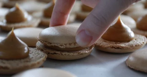 Close up shot of connecting two halves of macaroons with caramel cream Stock Footage 81900895