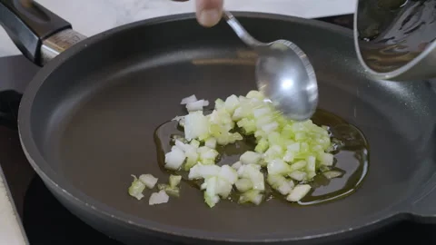 Close-up shot, cook puts chopped onions in a pan with olive oil. Stock Footage 274471461