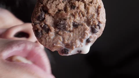 Close-up shot of cookie and milk as someone takes a bite, showing texture and Stock Footage 297650616