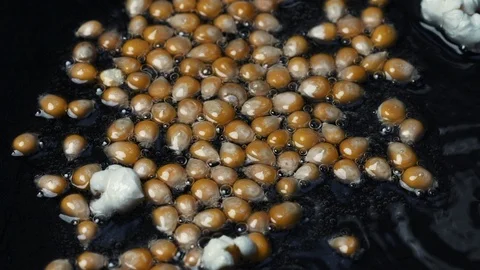 Close-up shot on cooking popcorn in a pan with hot oil at 100 fps Stock Footage 112561591