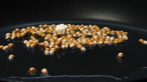 Close-up shot on cooking popcorn in a pan with hot oil at 100 fps Stock Footage 112563042