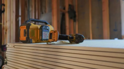 A close-up shot of a cordless drill resting on a sheetrock surface in a Stock Footage 299813242