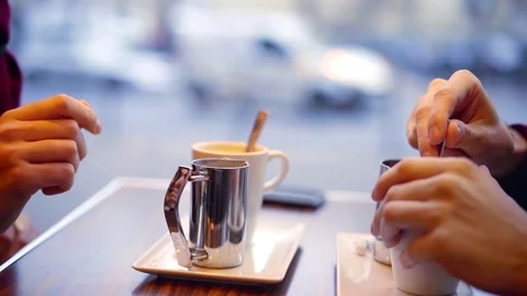 Close-up shot of a couple with coffee in a cafe, sitting by the window with look Stock Footage 98887672