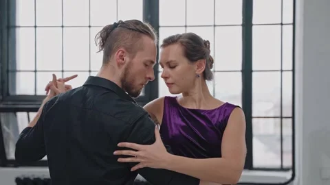 Close shot of couple dancing tango in grey studio against large windows Video stock 168630431