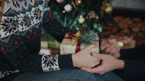 Close up shot of couple's hands in hands and a gift on the knee Vidéo 104220748