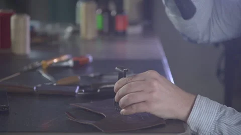 Close-up shot of craftsman hands making holes in small piece of leather. 스톡 동영상 130215710