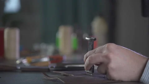 Close up shot of craftsman hands making holes in small piece of leather. 스톡 동영상 130215765
