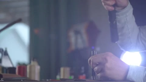 Close-up shot of craftsman hands making holes in small piece of leather. Vidéo 130215786