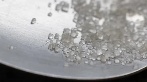 Close-up shot of crystals of sugar falling on a stainless steel surface of a spo Video stock 205518871