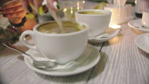 Close-up shot of a cup of coffee with milk. Pour sugar from the stick into a Stock Footage 155453426