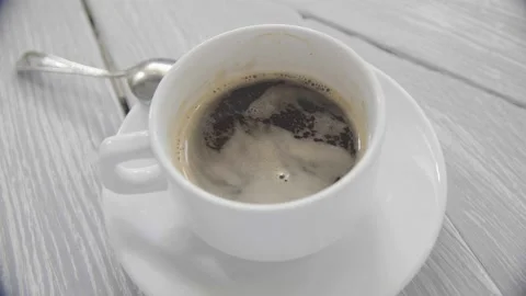 Close-up shot of a cup of coffee with milk. Pour sugar from the stick into a Stock Footage 155453600