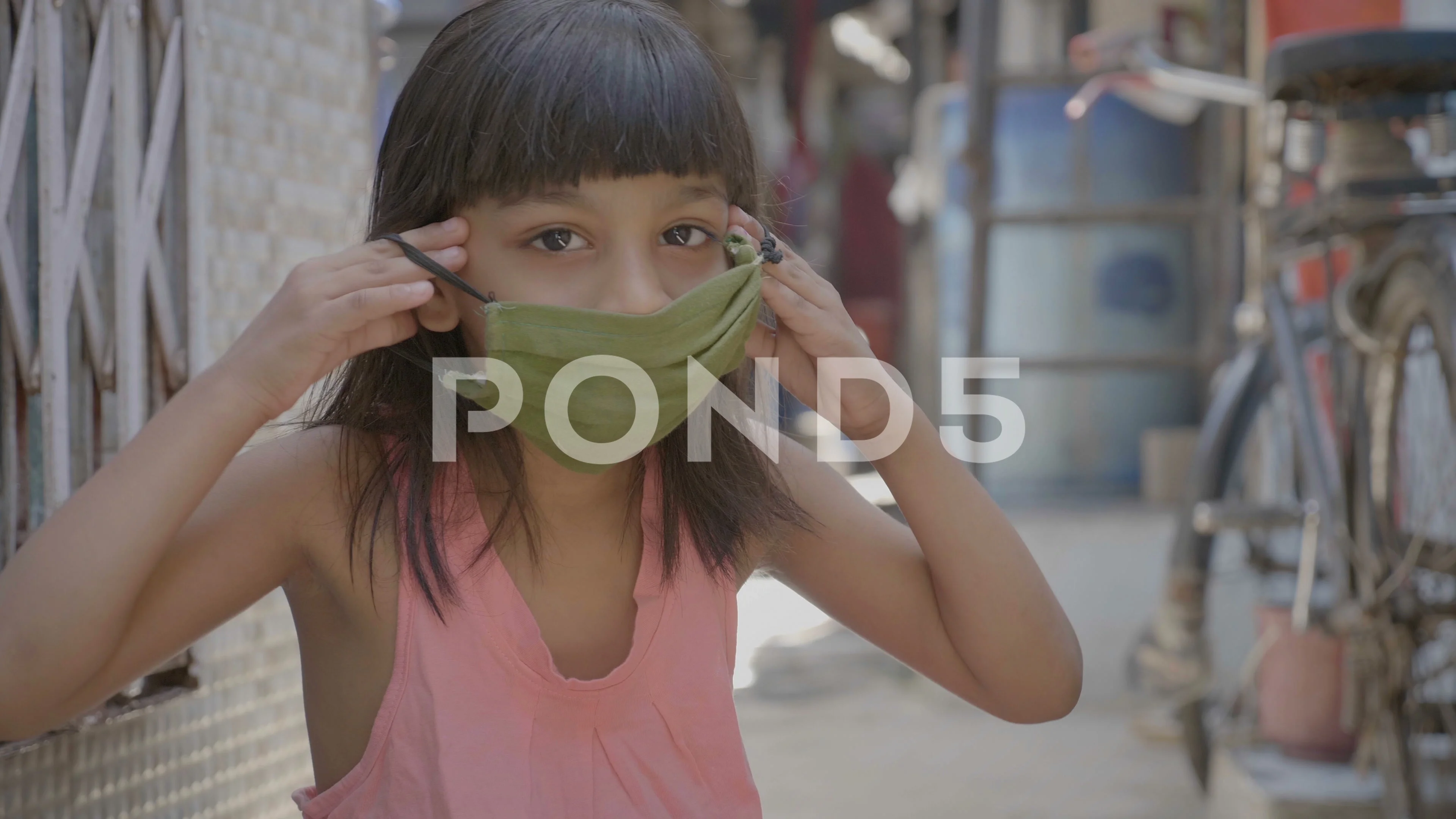 A close shot of cute Indian girl wearing or putting a face mask