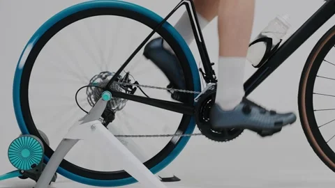Close shot of a cyclist's legs training on an exercise bike in white studio Video stock 171118422