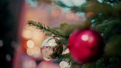 Close up shot of decorative silver bauble hanging on a decorated pine tree .. Vidéo 335260148