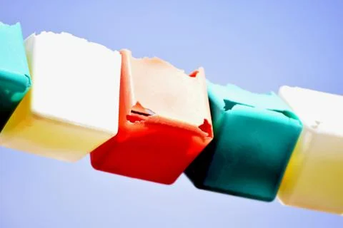 A close shot of different colored cubes on a rope with a clear sky in the bac Stock Photos