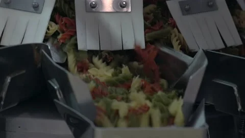 Close shot of a different colored macaroni moving to a packing machine Stock Footage 154696430