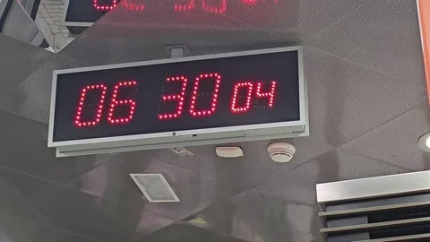 A close up shot of a digital clock displaying 06 30 00 in red digits. Video stock 312003152