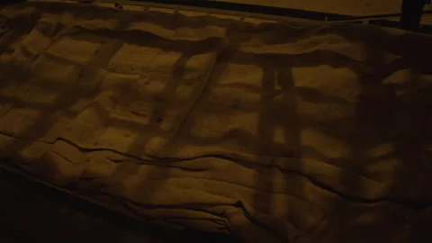 Close up shot of dimly lit bunk bed with a rough, coarse brown fabric laid loose Vídeo Stock 301031274