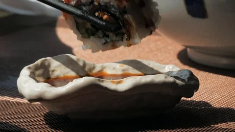 Close-up shot of dips the rolls into the soy sauce.. Chopsticks to dip the rolls Video stock 106492439