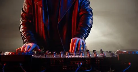 Close-up shot of dj's hands working on mixer controller, turning the knobs and Stockfoto's