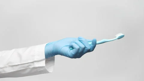 Close up shot of a doctor's hand in blue medical glove holding a toothbrush,  Video stock 238612096