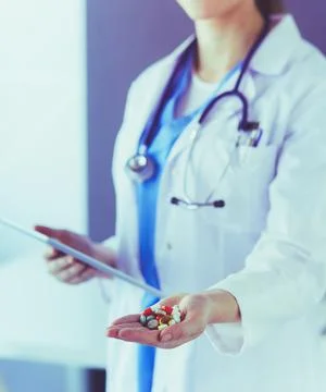 Close-up shot of doctor's hands holding pills and tablet at clinic. Stock Photos