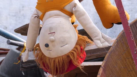 Close shot of a doll without one eye hanging upside down in a storeroom Stock Footage 146152855