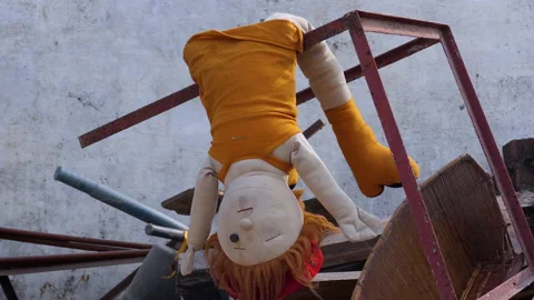 Close shot of a doll without one eye hanging upside down in a storeroom Stock Footage 146152870