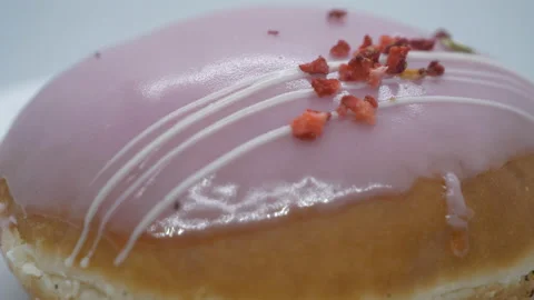 A close up shot of a donut with strawberry glazing. Stock Footage 201212081