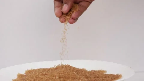 Close shot of dropping sugar from hand over heap of brown sugar Stock-Footage 148220527