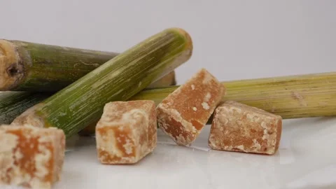 Close shot of dropping sugarcane jaggery over a white background Stock Footage 148220473