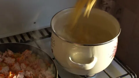 A close-up shot of dry pasta being poured into a large pot of boiling water.. Video stock 345751014