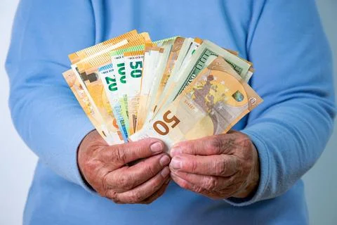 A close-up shot of an elderly persons hands holding a fan of Euro and US Do.. Stock Photos