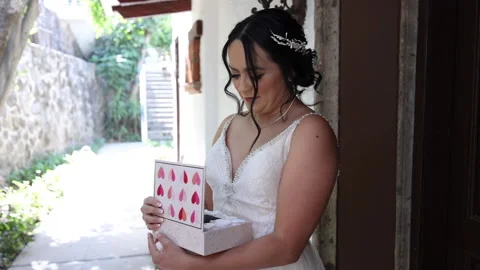 Close-up shot of elegant bride unpacking wedding present and feeling curious Stock Footage 235770764