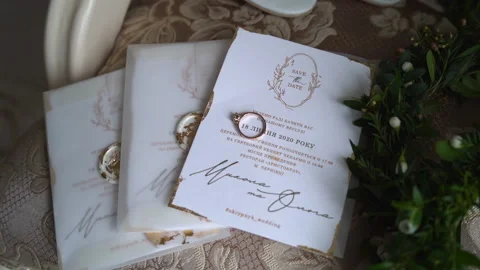 Close shot of elegant wedding invitations. Beautiful golden rings and greenery Stock Footage 148737009
