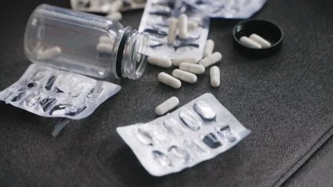 Close up shot of empty blister packs and jar of pills on sofa near unconscious Stock Footage 220213644