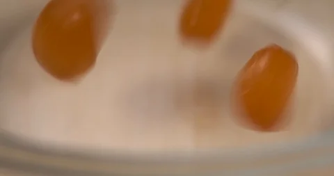 Close-up shot of empty transparent bowl, orange sweets, caramels poured into it Stock Footage 119054338