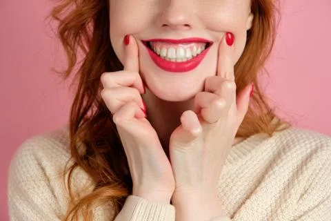 A close shot of the face of a red-haired girl with red manicure and lipstick Stock Photos