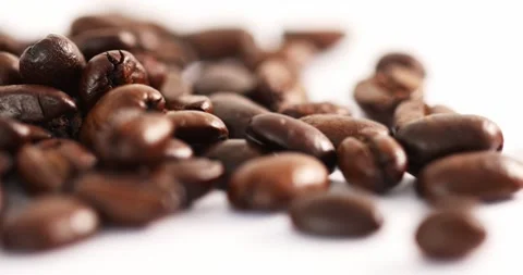 Close up shot of falling coffee beans on a white background spinning on a table Stock Footage 152762832