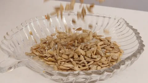 Close shot of falling sunflower seeds into transparent glass bowl Vídeo Stock 160885565