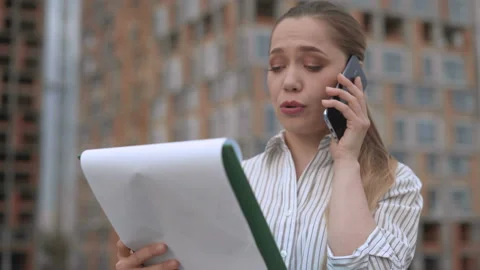 Close-up shot. female engineer talking on the phone comparing a construction Stock Footage 123446477
