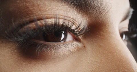 Close up shot of female eyes with makeup on eyelashes and dark brown irises, image size:480x253