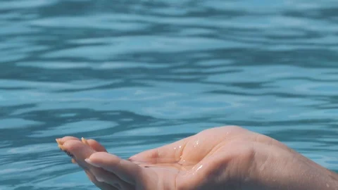 Close-up shot of female hand playing with water, catching it with fingers and Stock-Footage 101282025