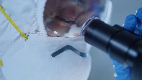 Close Up Shot of Female Lab Worker in Mask Using Microscope Stock Footage 128862972