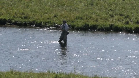 A fisherman casting a silver tipped spinner into a clear mountain stream