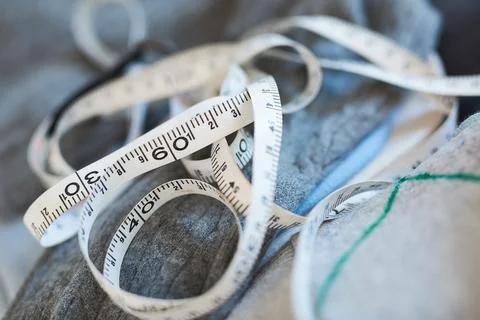 Close up shot of flexible white measuring tape lying on grey wool fabric in d Stock Photos