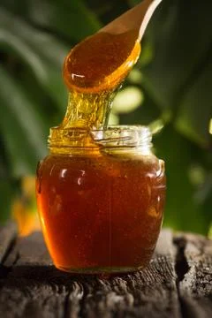 Close-up shot of flowing honey over yellow background Stock Photos