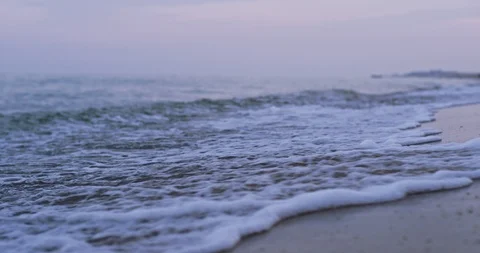 A close shot of the foamy waves hitting the sand. 4k Stock Footage 115320223